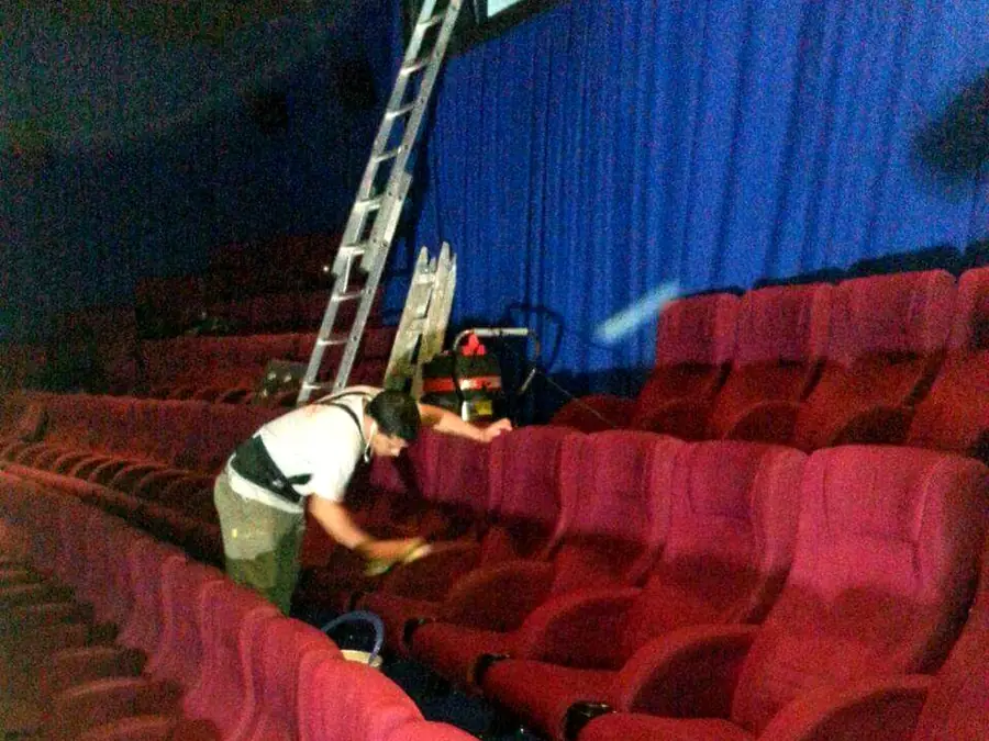 Operario de Carpet Clean limpiando butacas en una sala de cine