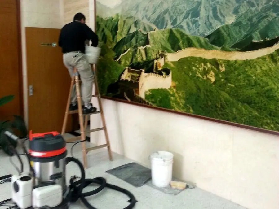 Operario de Carpet Clean limpiando una oficina subido a una escalera