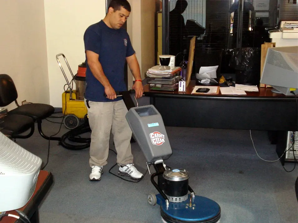 Operario de Carpet Clean con la máquina rotativa de la empresa en una oficina